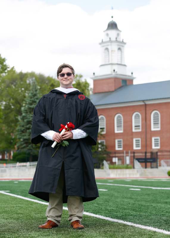 a man in a graduation gown holding a rose
