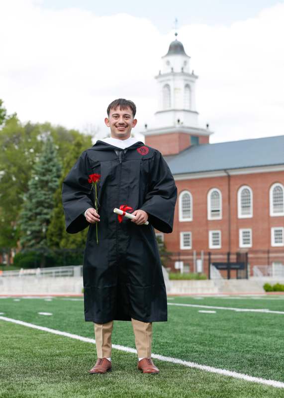 a man in a graduation gown holding flowers
