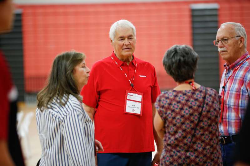 a man in a red shirt talking to a group of women