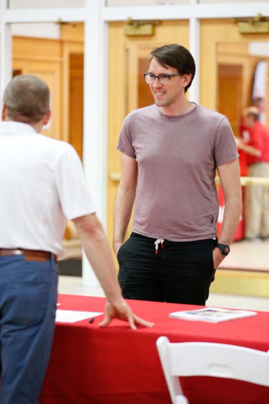 a man standing next to a table with a red tablecloth
