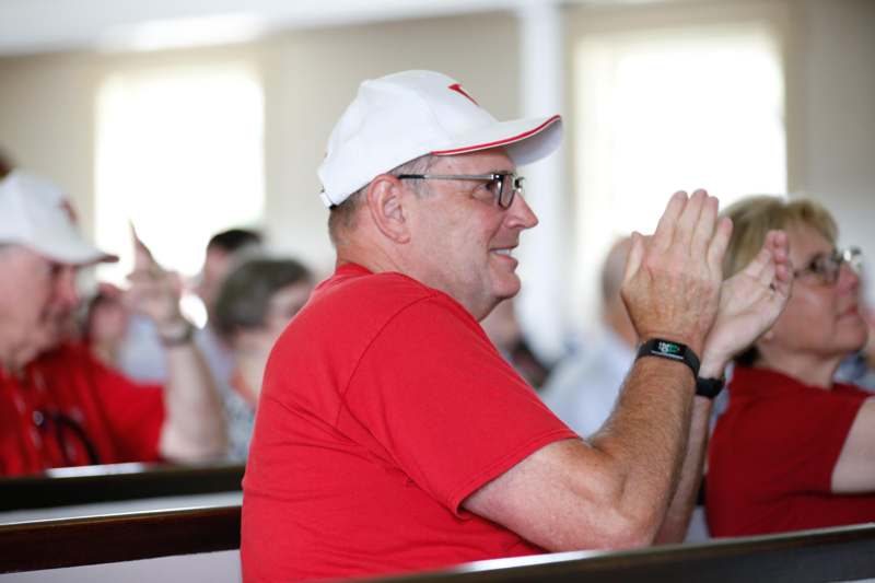 a man in a red shirt and white cap clapping