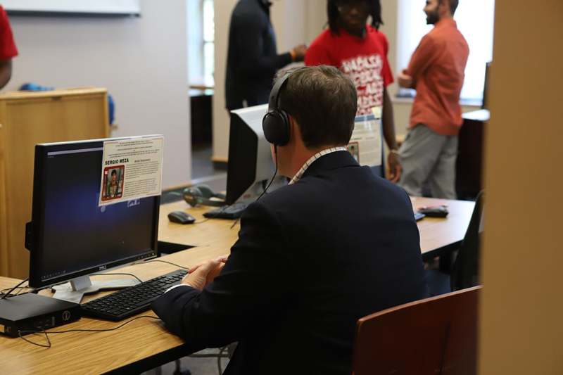 a man wearing headphones sitting at a desk with a computer