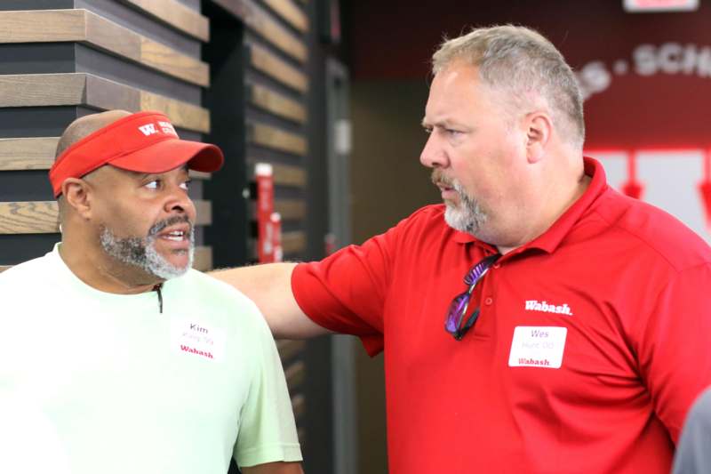 a man in a red shirt talking to another man