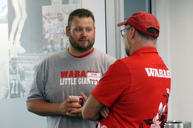 a man in red shirt talking to another man