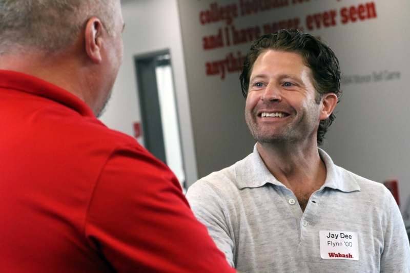 a man in a red shirt shaking hands with another man