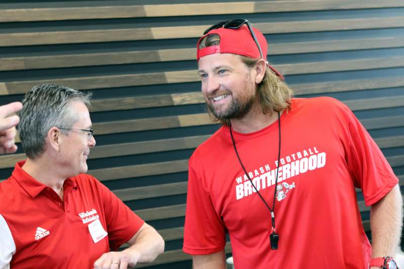 a man in red shirt and cap talking to another man