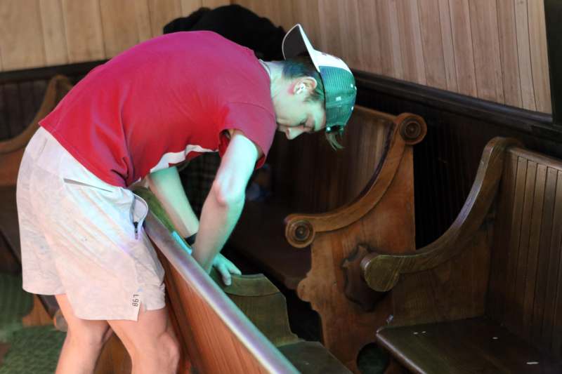 a man in a red shirt and white hat bending over a wooden bench