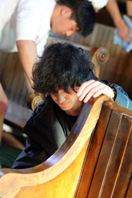 a man with black hair leaning on a bench