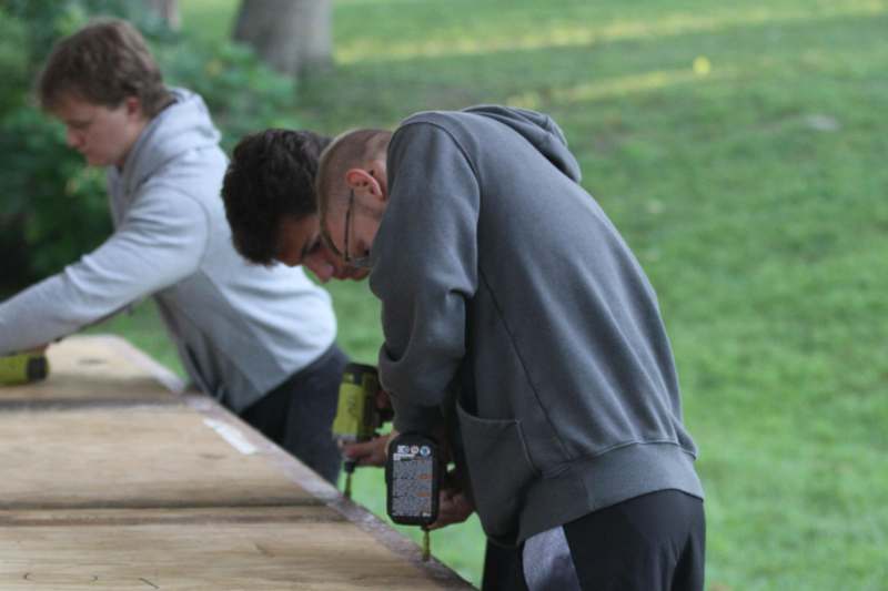 a group of men using drill to drill wood
