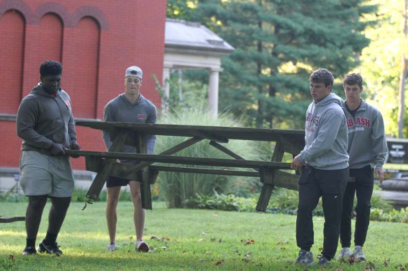 a group of men carrying a wooden bench