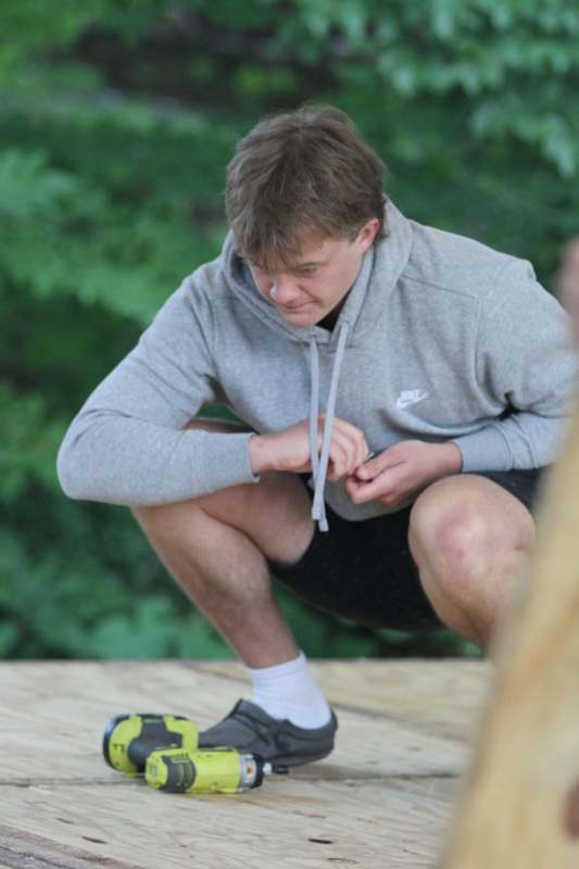 a man squatting on a wood surface