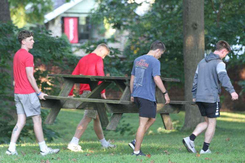 a group of men carrying a picnic table