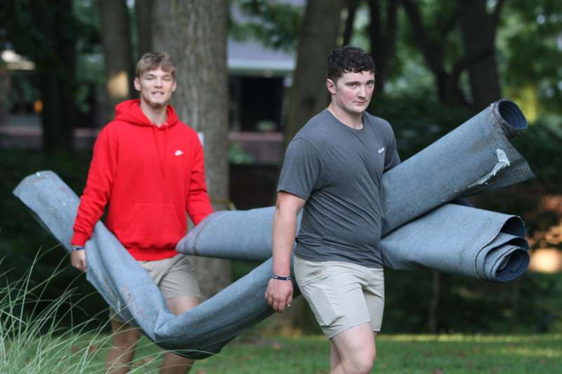 two men carrying a pile of carpet