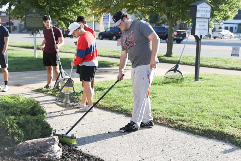 a group of people sweeping the sidewalk