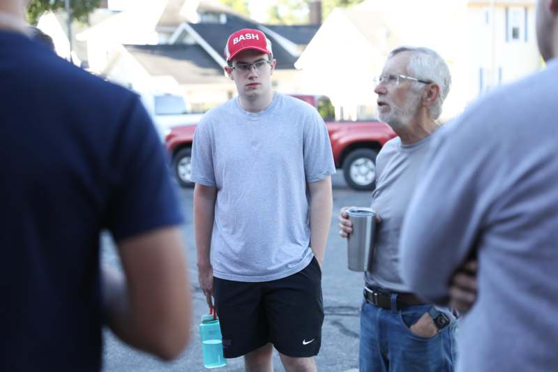 a man in a red hat standing in a parking lot with other men