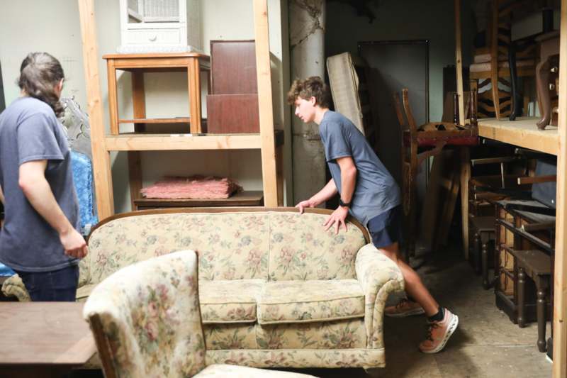 a man pushing a couch in a room