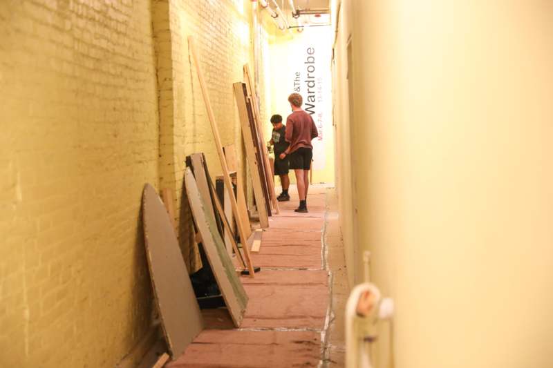 two men standing in a hallway with wood planks