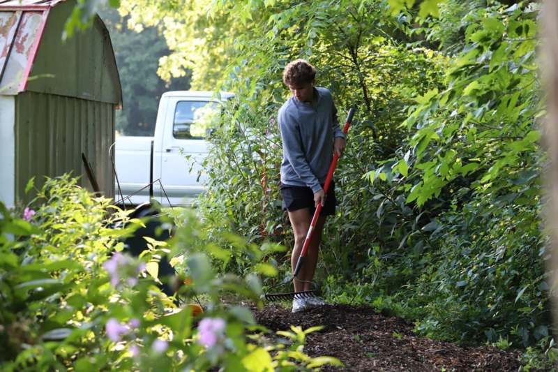a man holding a red shovel in a garden