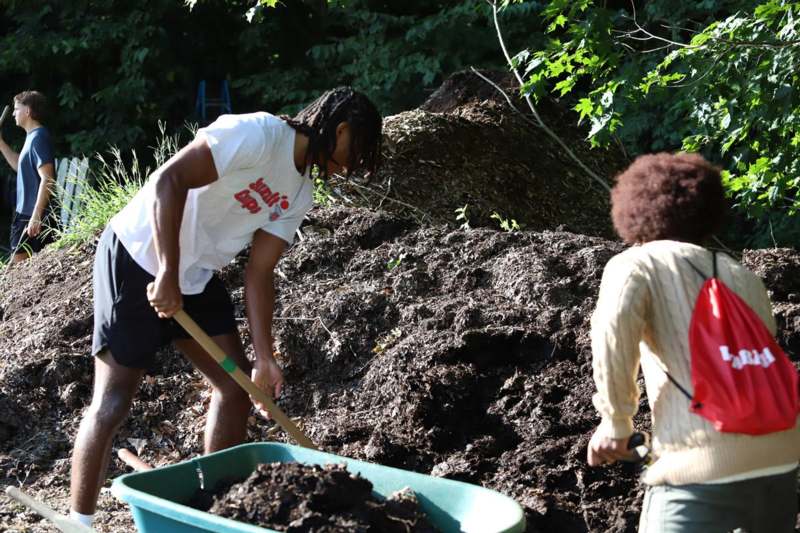 a man shoveling dirt into a wheelbarrow