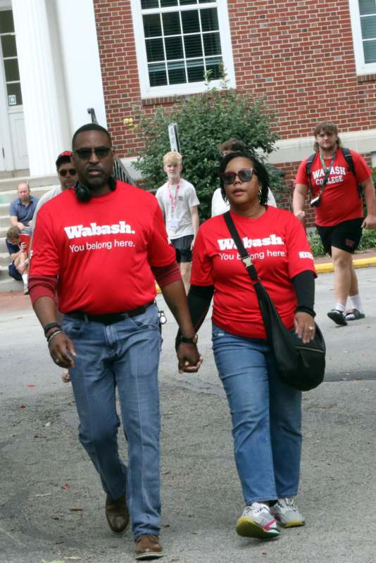 a man and woman holding hands and walking on a street