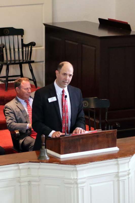 a man in a suit and tie standing at a podium