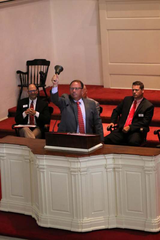 a man in a suit holding a bell up