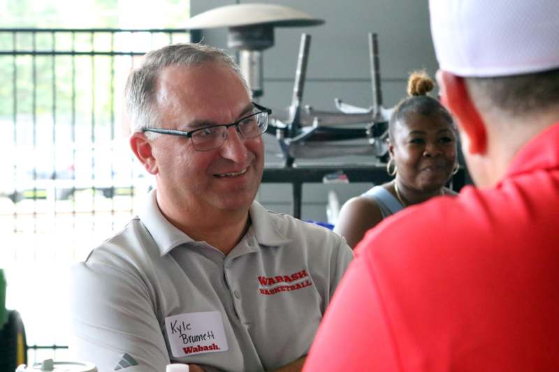 a man wearing glasses and a white cap talking to a woman