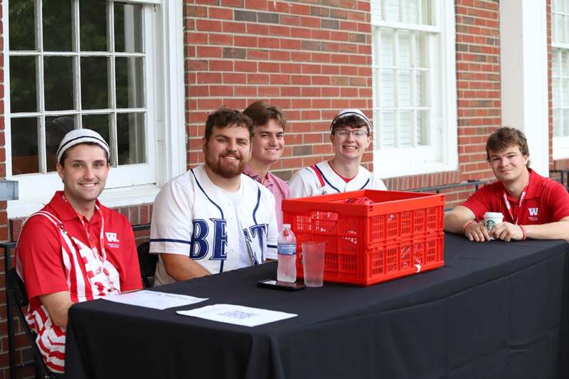 a group of men sitting at a table with a red plastic crate