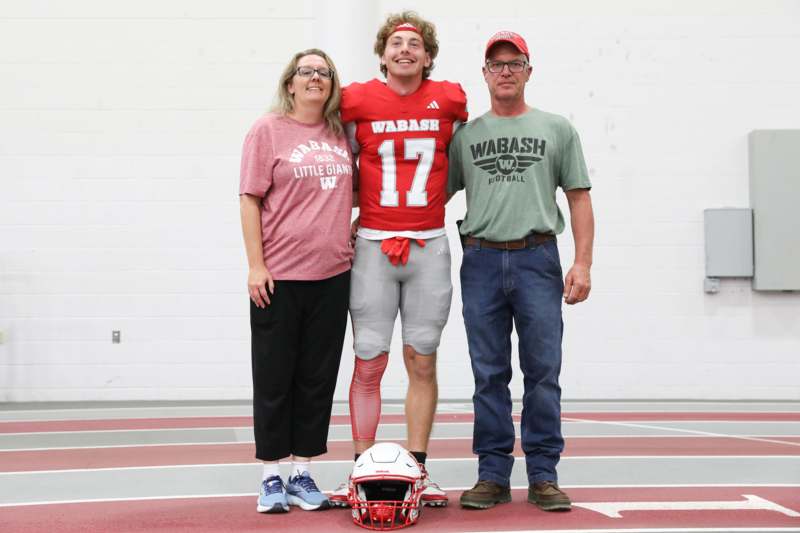a man standing with a football player and a couple of people standing on a track