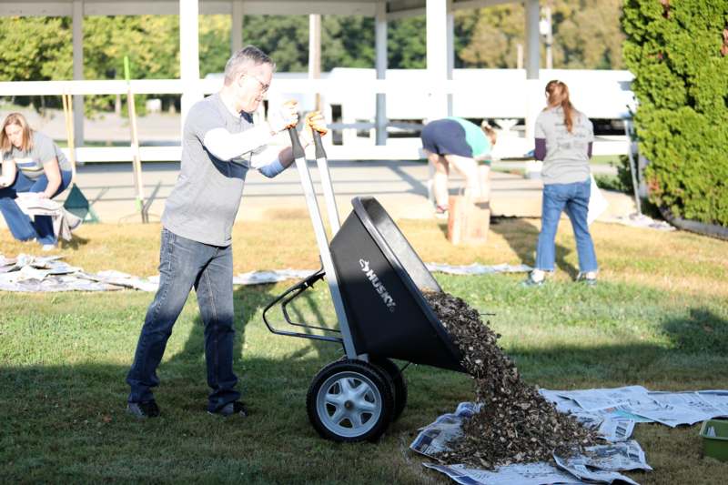 a man pushing a wheelbarrow full of leaves
