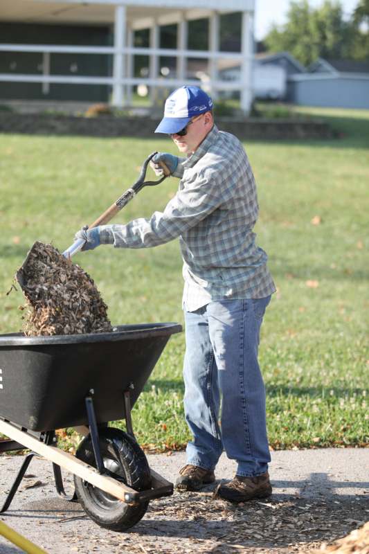 a man pushing a wheelbarrow full of leaves
