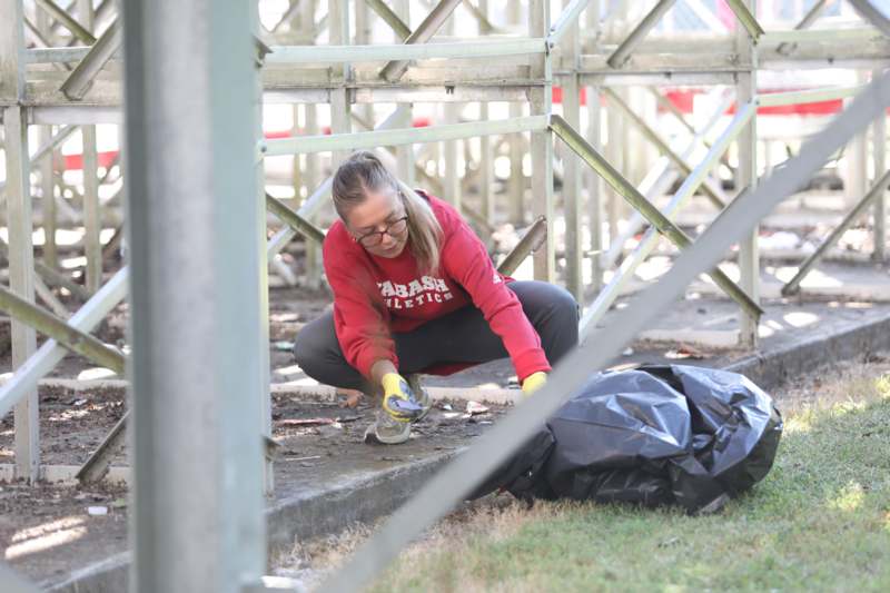a woman in a red shirt and black pants cleaning a sidewalk