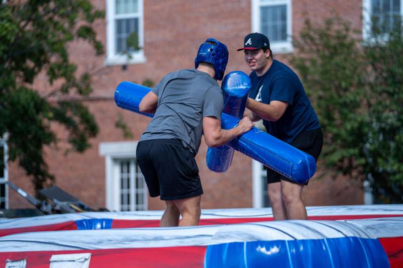 two men holding blue objects on a trampoline