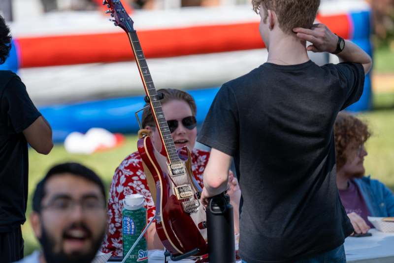 a man holding a guitar next to a person sitting at a table
