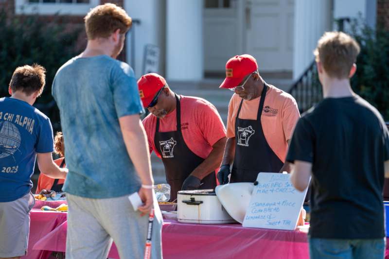 a group of men standing around a table with food