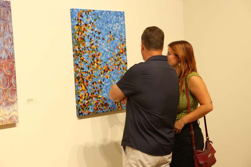 a man and woman looking at a painting