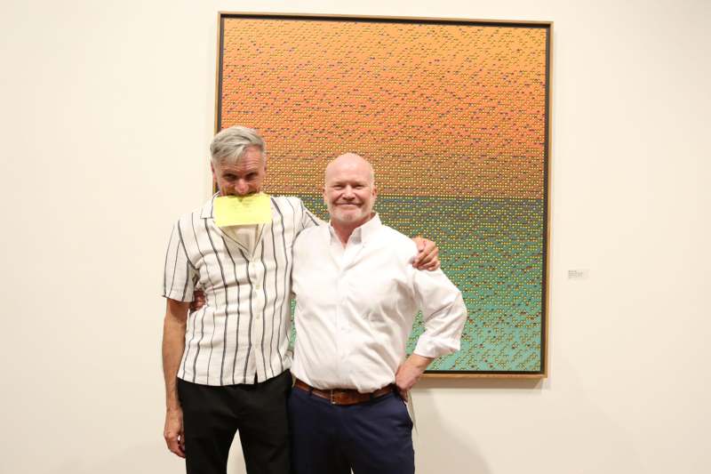 two men standing in front of a painting
