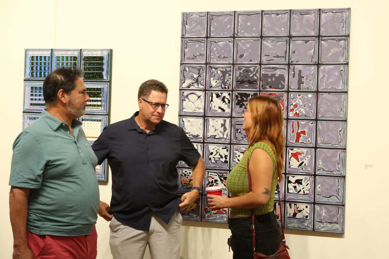 a group of people standing in front of a wall with art