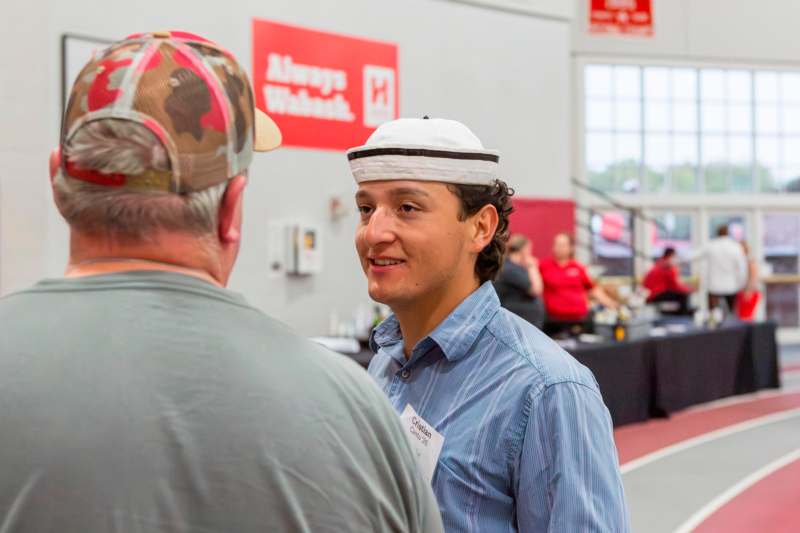 a man wearing a hat and a badge talking to another man