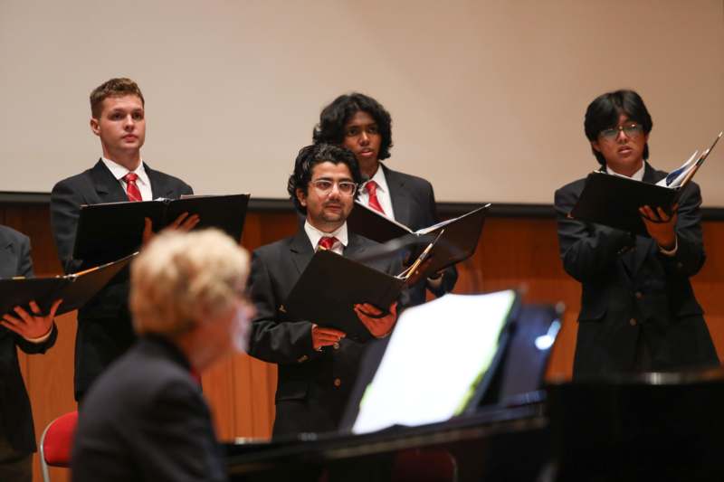 a group of men in suits holding music books