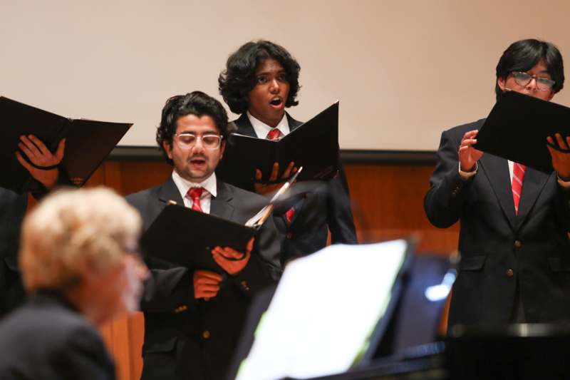 a group of people singing in front of a screen