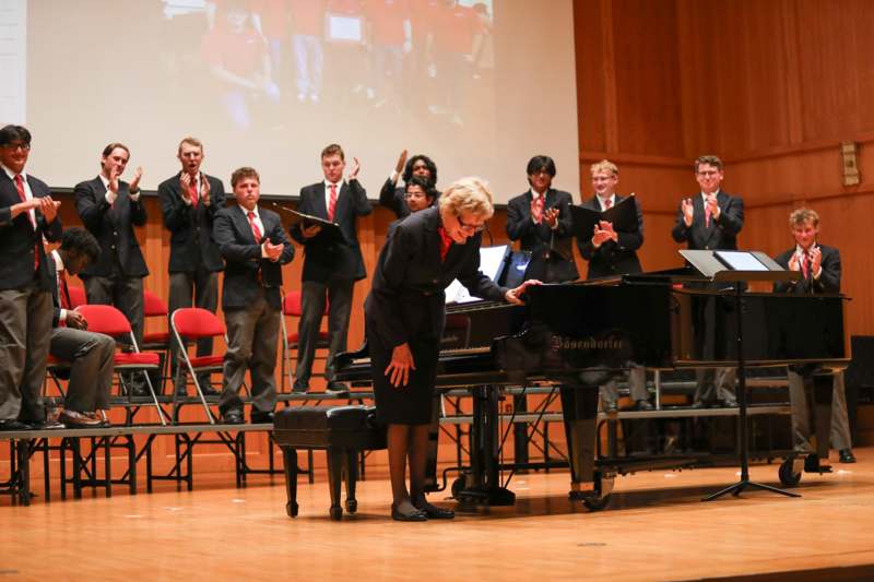 a group of people standing in front of a piano