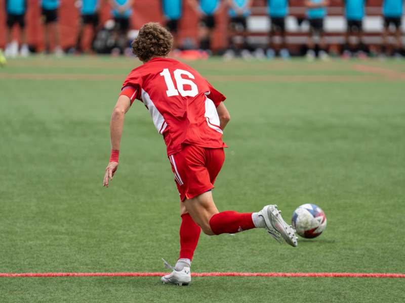 a man in red uniform kicking a football ball