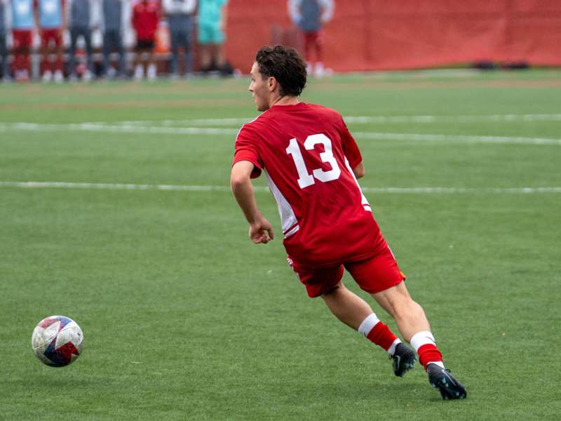 a man in a red uniform kicking a football ball