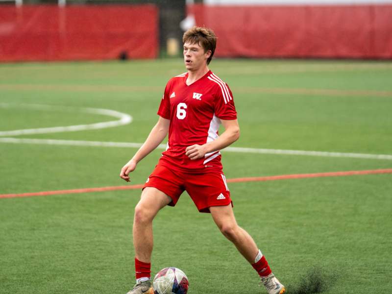 a man in a red uniform kicking a football ball