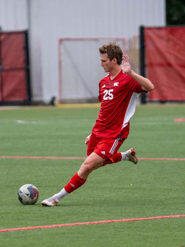 a man in a red uniform kicking a football ball