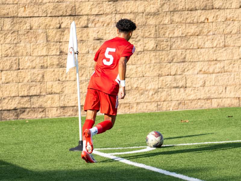 a man in a red uniform kicking a football ball