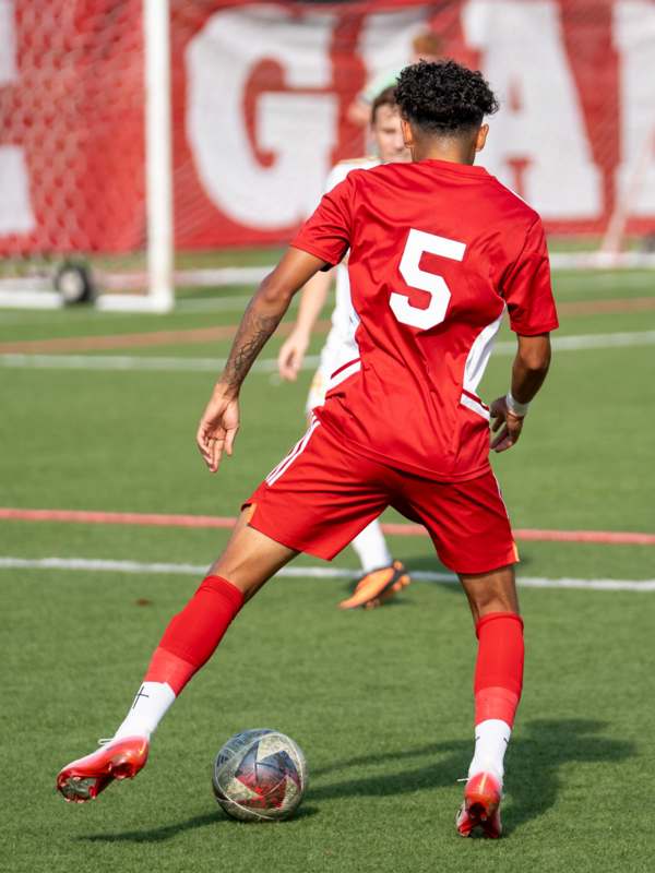 a man in a red uniform kicking a football ball