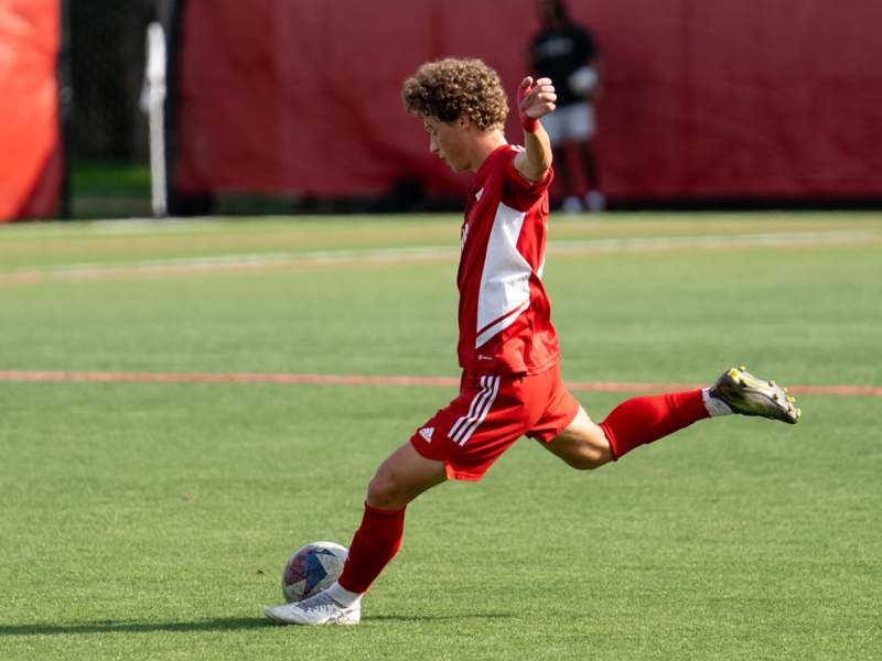 a man in a red uniform kicking a football ball