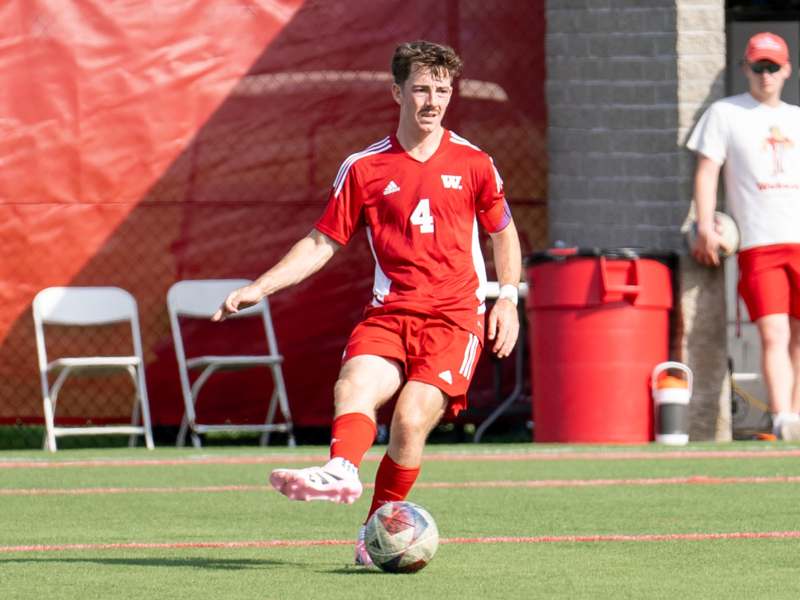 a man in a red uniform kicking a football ball